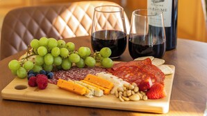 A wooden table with a charcuterie board, two glasses of red wine, and a bottle of wine. - Peaceful family hideaway near Doolin with Aran views & stunning sunsets. (Doolin)