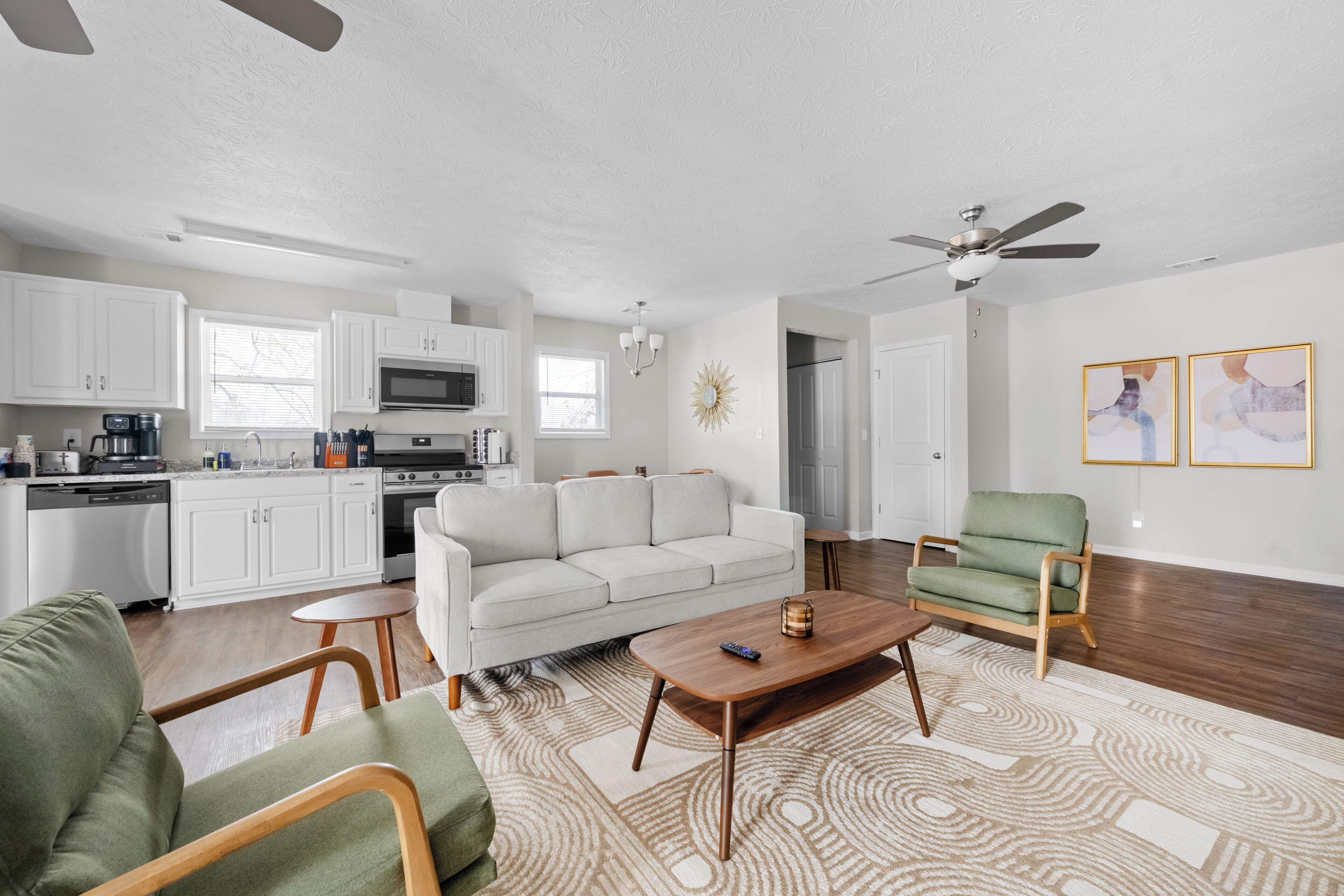 A modern living space with a kitchen, a sofa, a coffee table, and a green armchair.