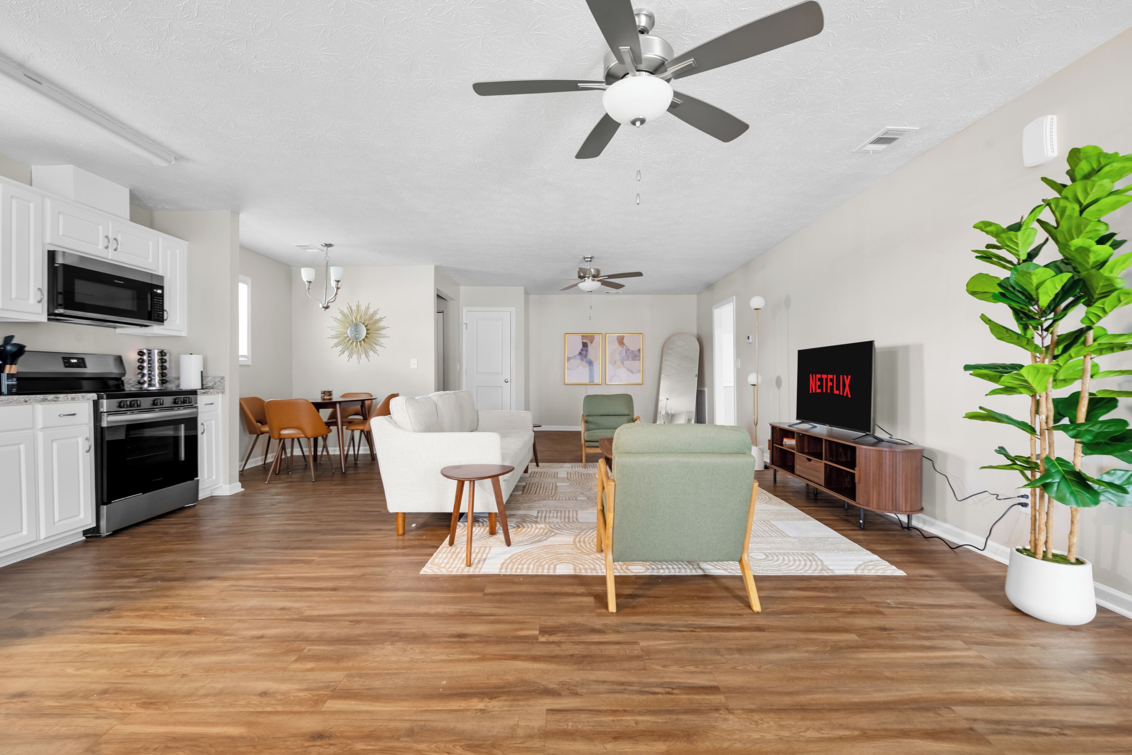 A modern living room with a dining area, kitchen, and entertainment unit.