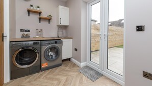 Eine kleine Küche mit Waschmaschine, einer Holzausziehtafel, einem eingebauten Backofen und einer Glastür zum Patio.