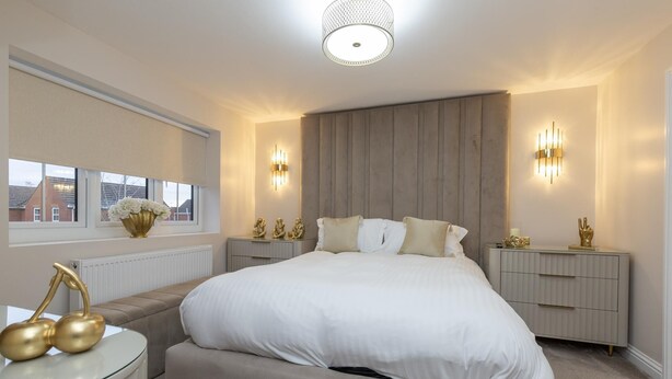 Ein Schlafzimmer mit einem großen Bett, Nachttischen, einem Fenster und einer Heizung.