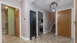 Ein Flur mit Fischgrätparkett, Holztüren und einer Treppe, die zu einer oberen Ebene führt.