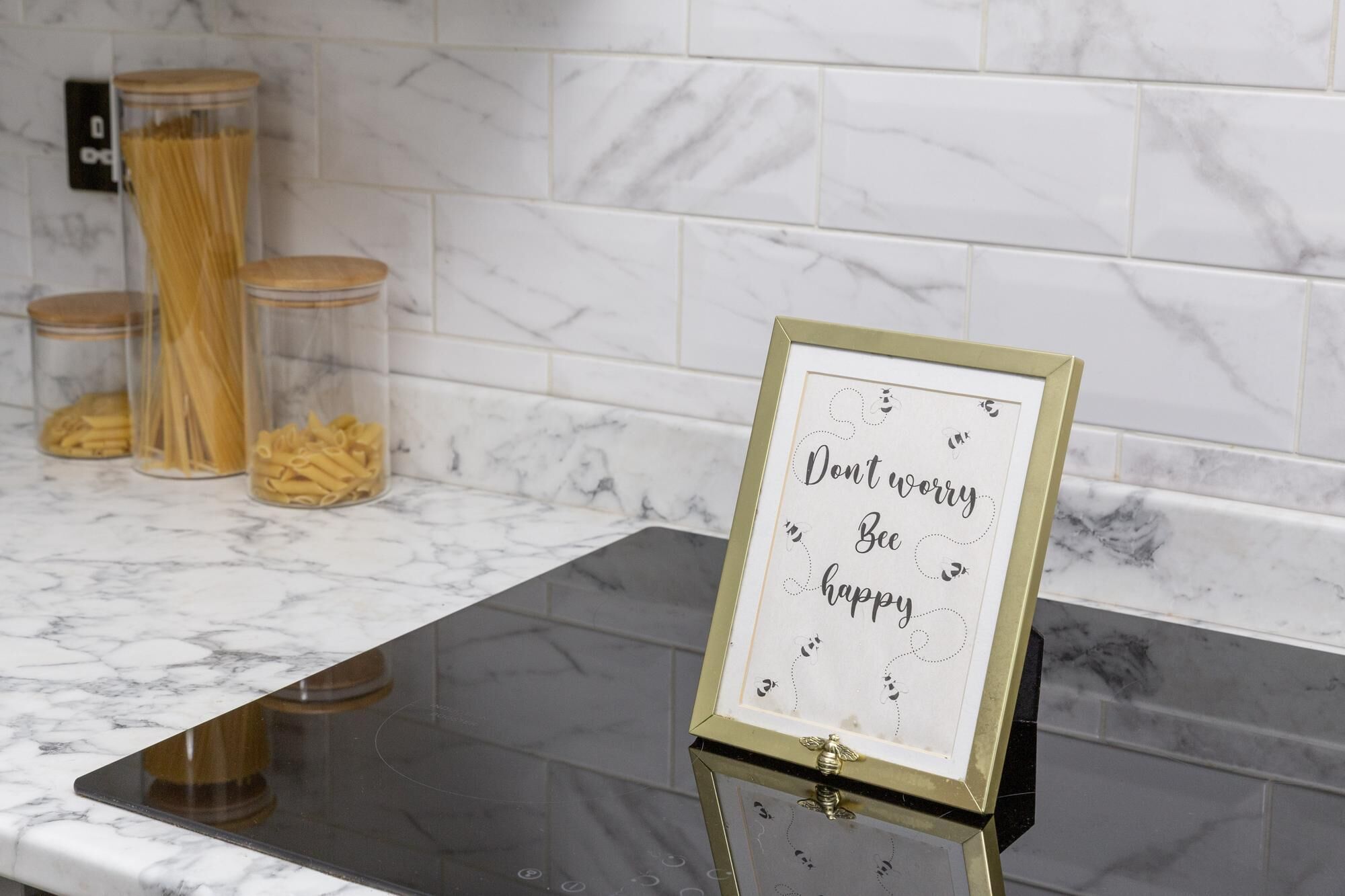 A kitchen counter with pasta containers and a framed inspirational quote.