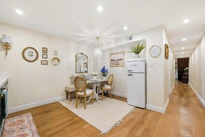 Een moderne keuken met een witte koelkast, houten kasten en een eethoek met een tafel en stoelen.