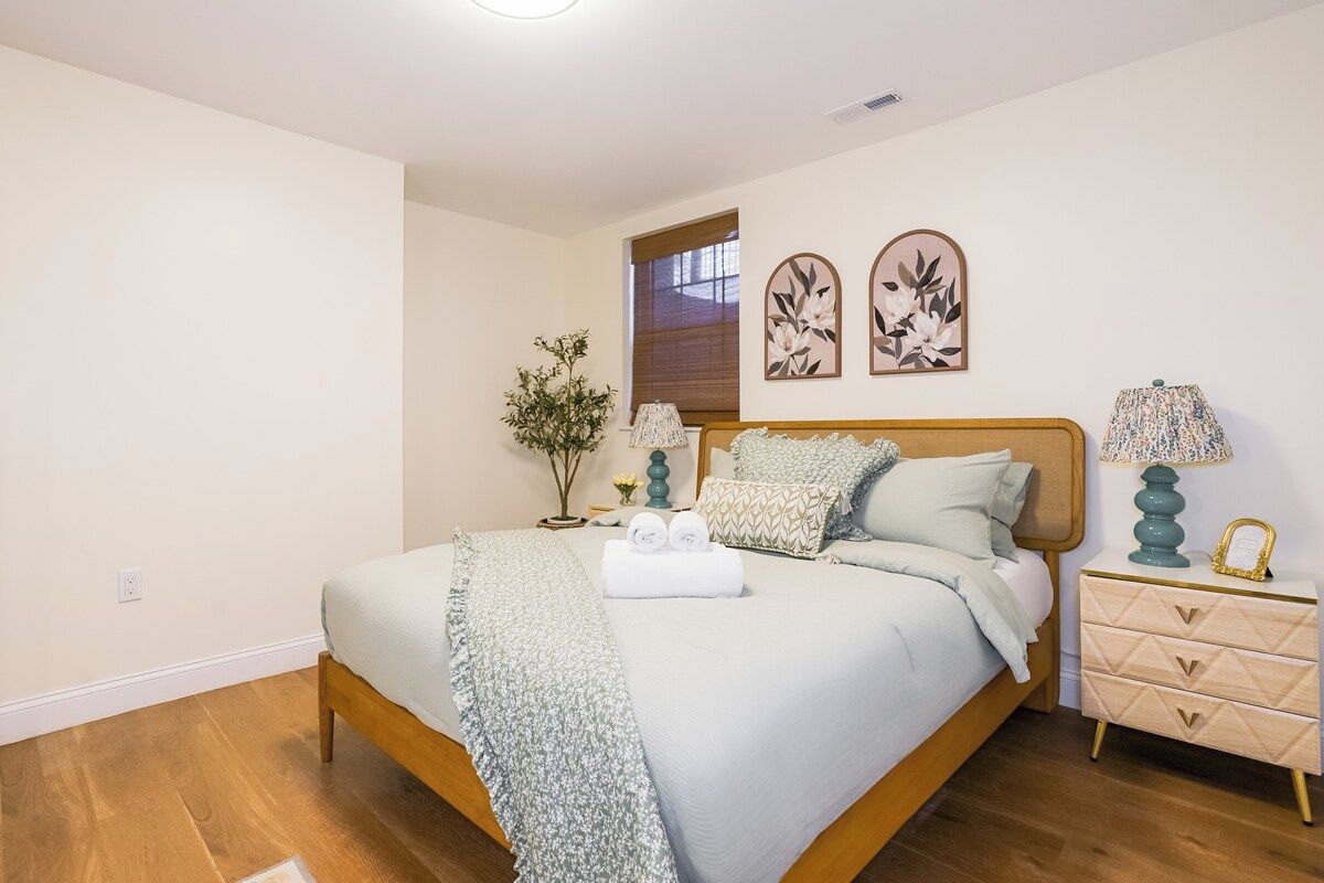 A bedroom with a bed, bedside tables, a window, and wall art.