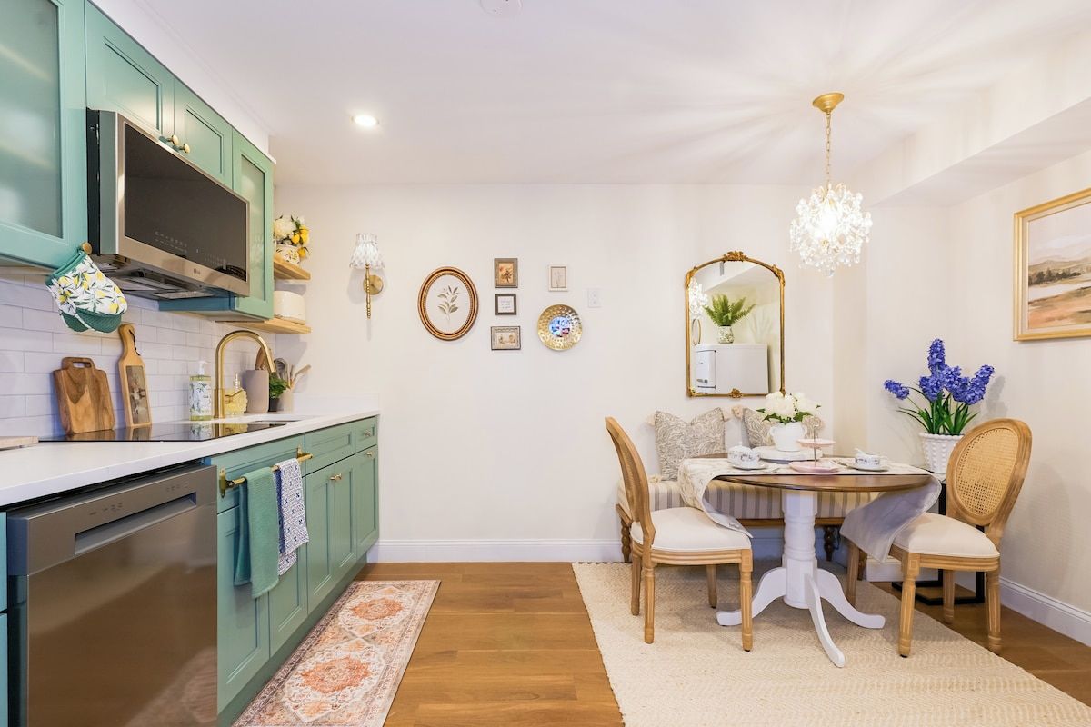 A kitchen with teal cabinets, a stainless steel oven, and a dining area with a round table and chairs.