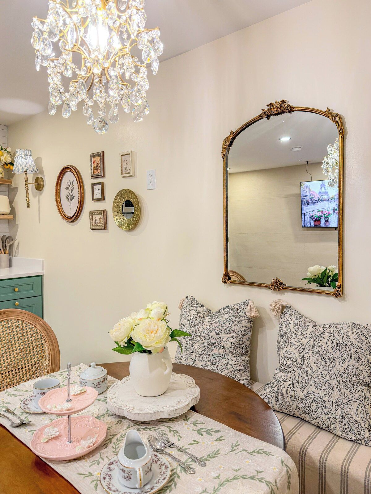 A dining area with a chandelier, a large mirror, and a television mounted on the wall.