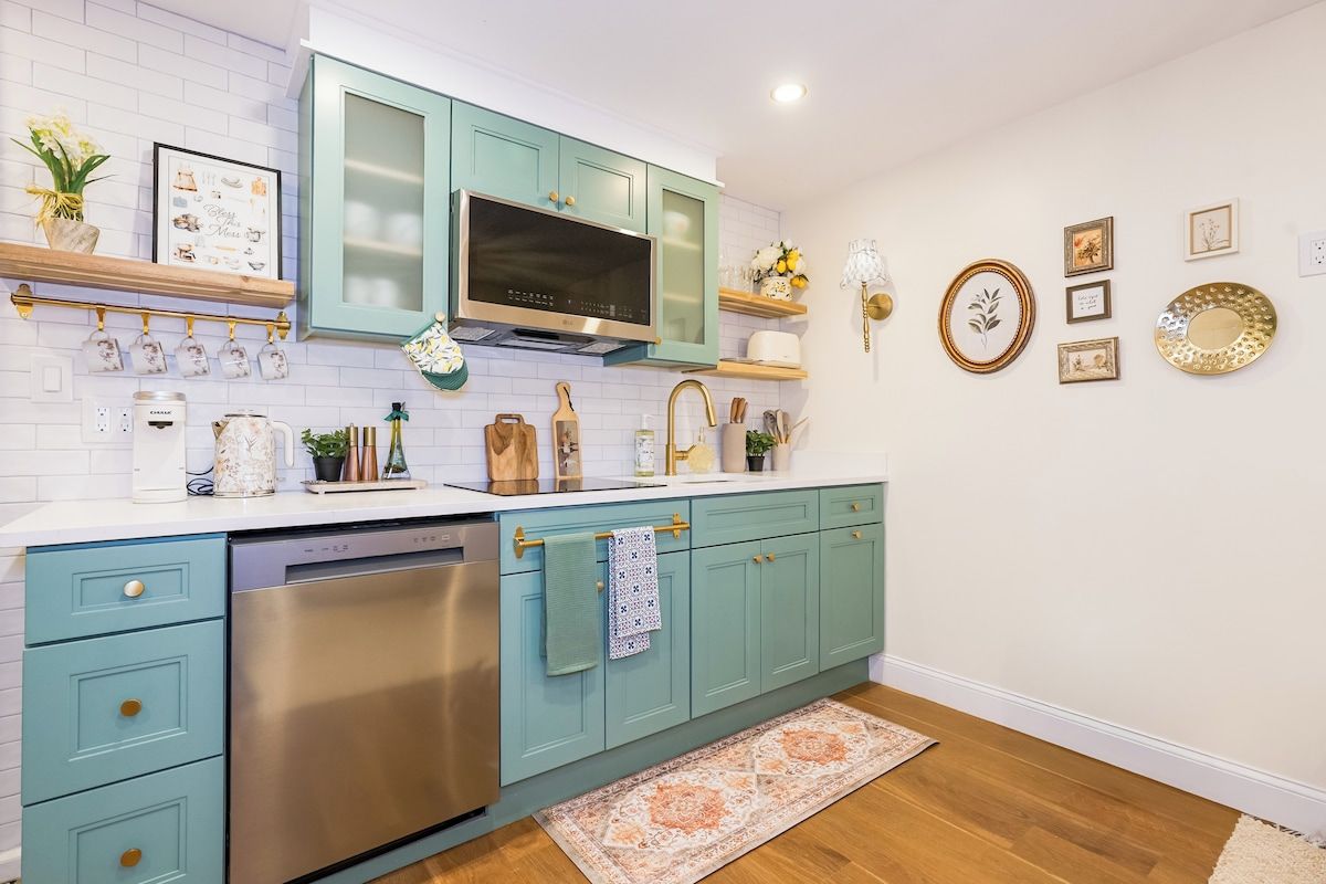 A kitchen with teal cabinets, stainless steel appliances, and decorative wall art.