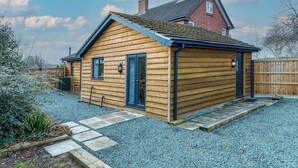 A wooden cabin with a sloped roof, a front door, and a small porch area. - Cosy countryside lodge in quiet surroundings - Pass the Keys (Shrewsbury)