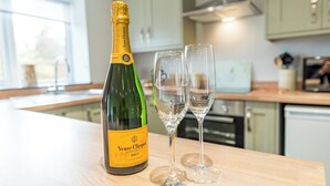 A bottle of Veuve Clicquot Brut champagne and two empty glasses on a kitchen counter. - Cosy countryside lodge in quiet surroundings - Pass the Keys (Shrewsbury)