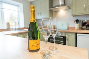 A bottle of Veuve Clicquot Brut champagne and two empty glasses on a kitchen counter. - Cosy countryside lodge in quiet surroundings - Pass the Keys (Shrewsbury)