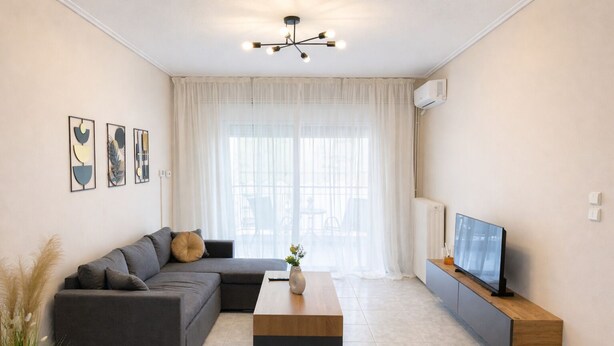 Un salon moderne avec un canapé d’angle, une table basse, un téléviseur à écran plat posé sur un meuble en bois et des œuvres d’art accrochées au mur.