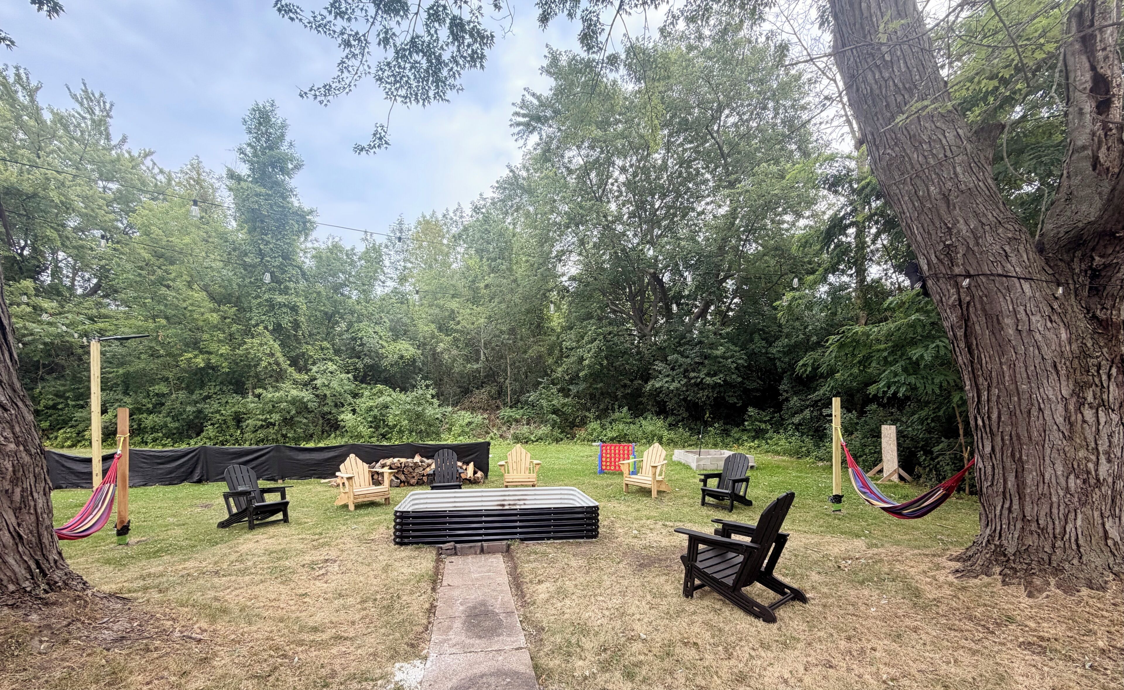 Un espace extérieur aménagé avec des chaises et une table, entouré d’arbres.