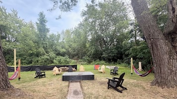 Un espace extérieur aménagé avec des chaises et une table, entouré d’arbres.