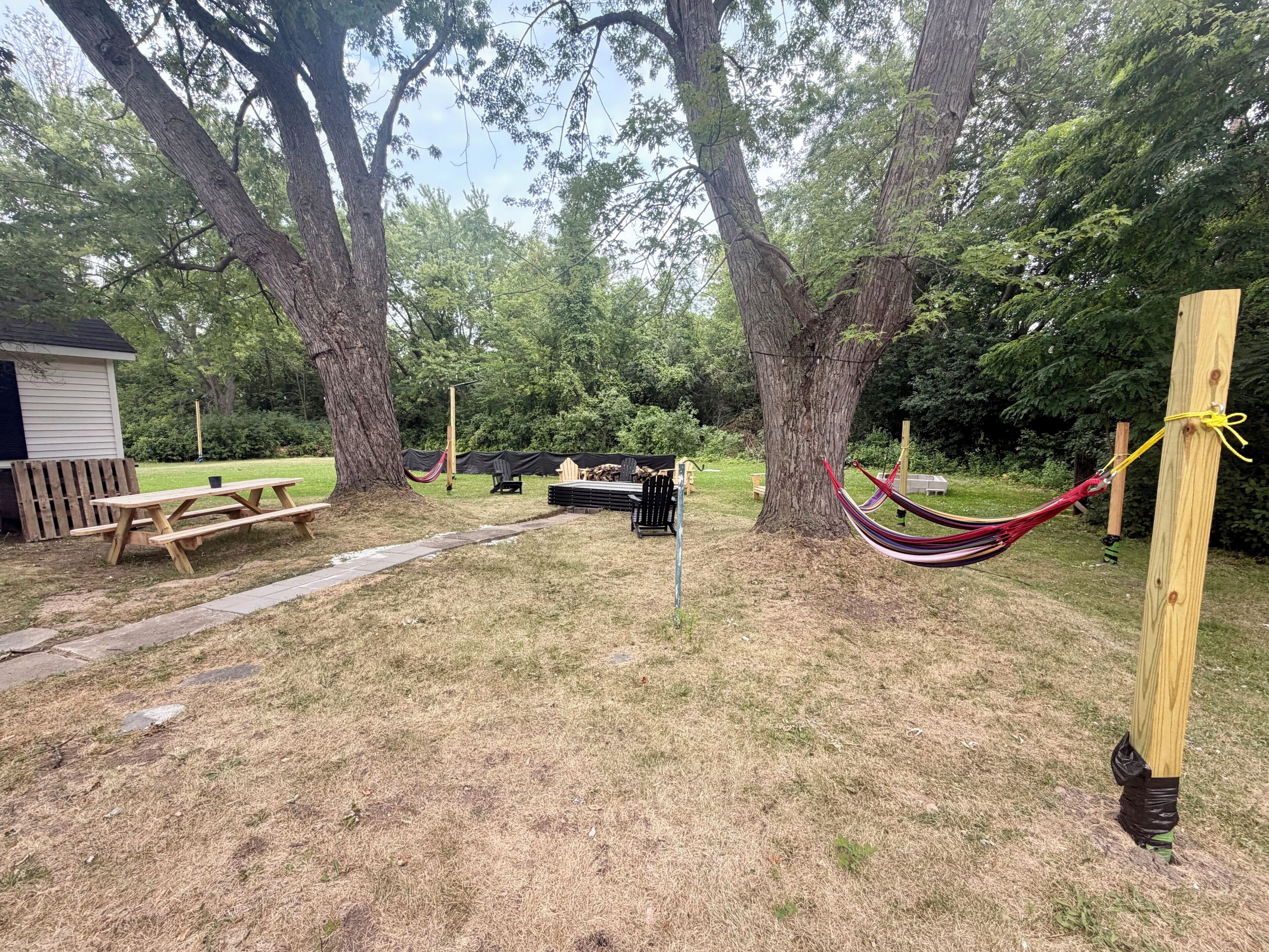 A picnic area with a wooden bench, picnic table, and hammock.