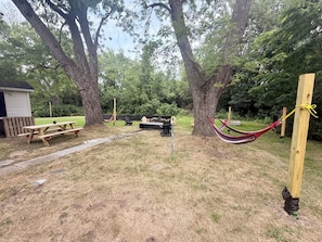 A picnic area with a wooden bench, picnic table, and hammock. - Spacious Country Retreat – Perfect for Families, Groups & Getaways (Plattsburgh)