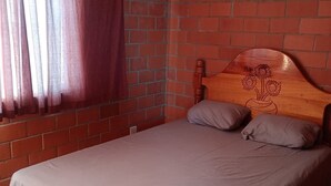 Ein Zimmer mit Backsteinwand, einem Bett mit Kopfteil und einem Fenster mit Vorhängen.