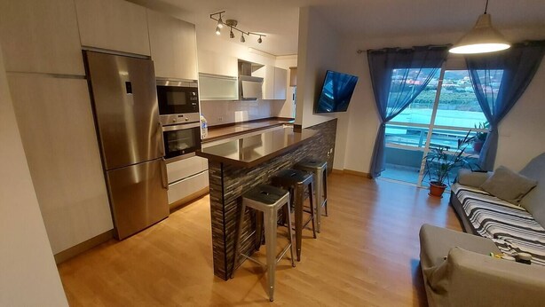 A modern kitchen with a central island, stainless steel appliances, and a dining area with bar stools. - Bright apartment in Los Llanos downtown (Los Llanos)