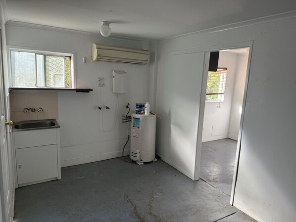 A small, clean kitchen with a sink, a window, and an air conditioning unit.