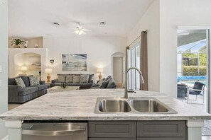 A modern kitchen with a marble countertop, stainless steel sink, and built-in dishwasher. - Saltwater Pool-Windsor Palms Resort, Backing Conservation Area-6 Miles to Disney (Kissimmee)