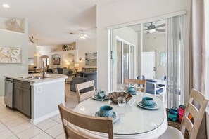 A modern kitchen with a central island, a dining area with a round table, and a living space with a sofa and a TV. - Saltwater Pool-Windsor Palms Resort, Backing Conservation Area-6 Miles to Disney (Kissimmee)