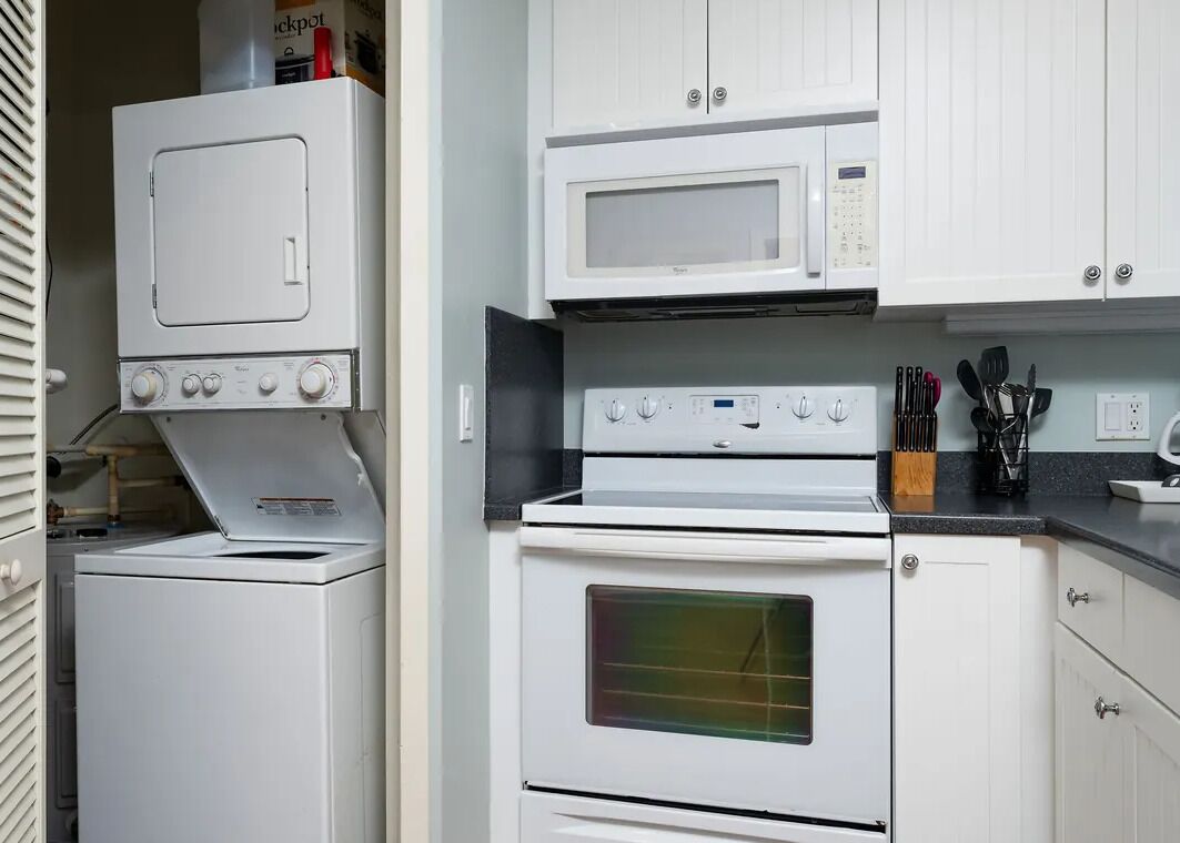 A compact kitchen with a microwave, oven, and stacked washer-dryer unit.