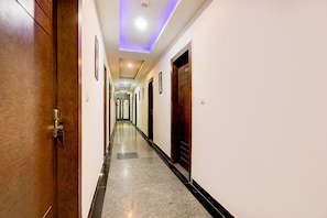 Un pasillo de hotel con puertas de madera, cuadros enmarcados y suelo de baldosas.