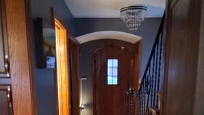 Un couloir avec des portes en bois, un lustre et un escalier.