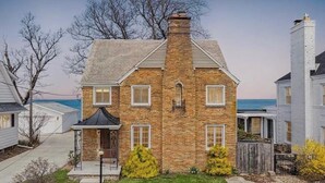 Une maison en briques avec une cheminée, un porche et une vue sur l’océan.