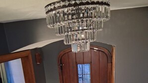 Une porte en bois avec une fenêtre, un lustre et une chaise bleue à l’arrière-plan.