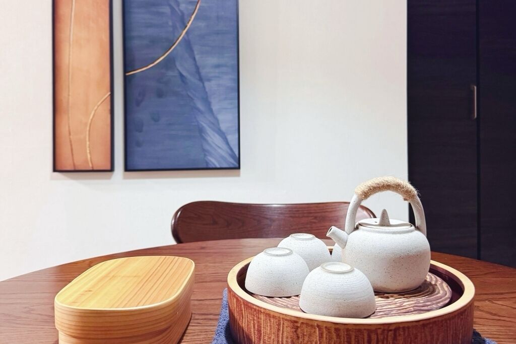 A dining table with a wooden bowl containing teapots and a wooden bowl.