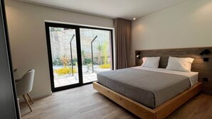 Un dormitorio moderno con una cama grande, un ventanal corredero a un jardín y un diseño minimalista.