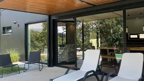 Un espacio exterior moderno con sillones de descanso y techo de madera.