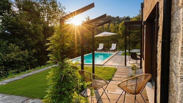 Un área de piscina con dos sillas de descanso, una pérgola y vistas a la piscina.