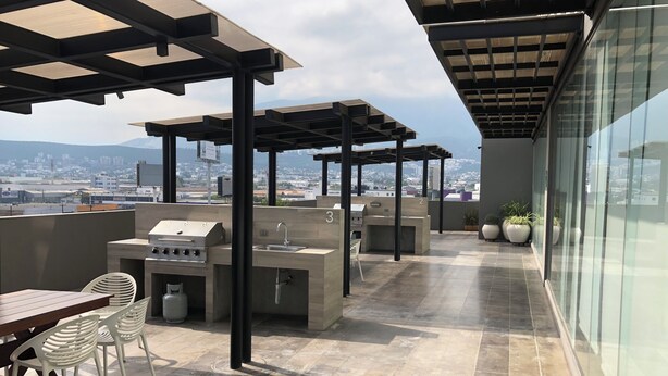 Terraza en la azotea con una parrilla, asientos y vistas de la ciudad.