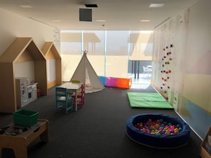 A children's playroom with a play kitchen, a teepee, and a ball pit.