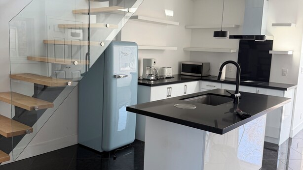 Uma cozinha moderna com uma ilha central, forno embutido e micro-ondas.
