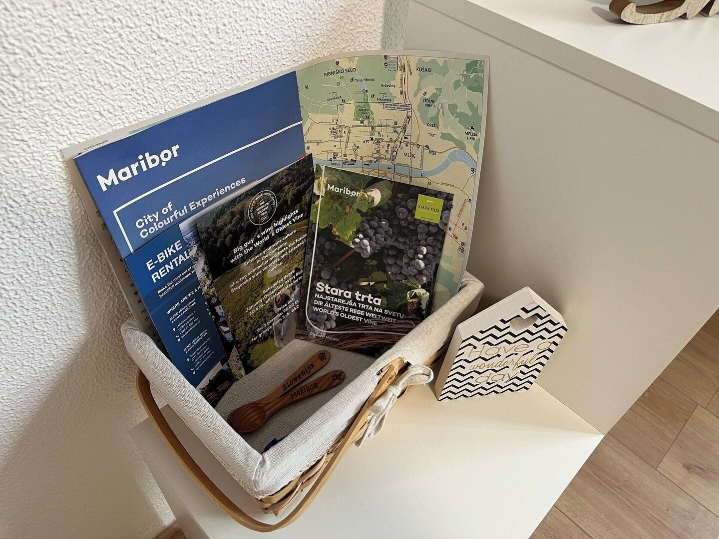 En korg som innehåller en broschyr, en karta och en träsked med inskriften ”Slovenien Maribor”.