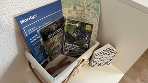 A basket containing a brochure, a map, and a wooden spoon with 'Slovenia Maribor' engraved on it. - Small and cozy apartment｜Free parking (Maribor)
