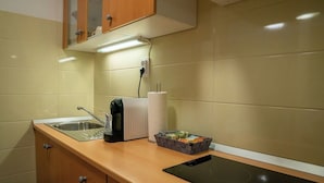 A kitchen with a sink, a toaster, a kettle, a box of tea bags, and a black induction cooktop.