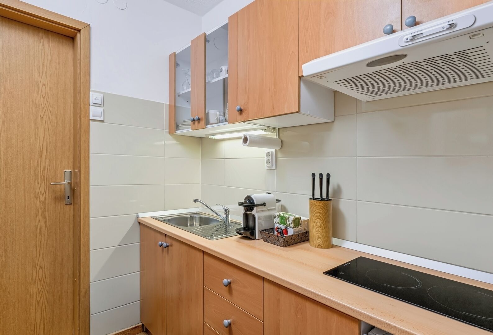 Een kleine keuken met een spoelbak, kookplaat en houten kastjes.