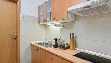 Een kleine keuken met een spoelbak, kookplaat en houten kastjes.