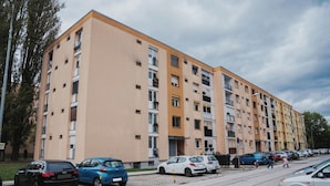 A multi-story residential building with a parking area in front.