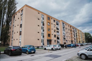 A multi-story residential building with a parking area in front. - Small and cozy apartment｜Free parking (Maribor)