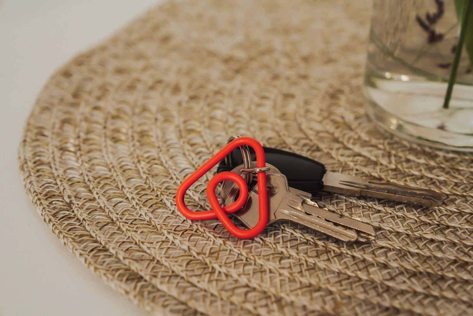 A woven placemat with keys and a red carabiner on it.