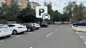 A parking lot with multiple cars, a large building in the background, and a sign indicating parking availability. - Small and cozy apartment｜Free parking (Maribor)