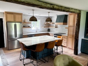 Une cuisine moderne dotée d’un îlot en marbre, d’appareils électroménagers en acier inoxydable et de meubles de rangement en bois.