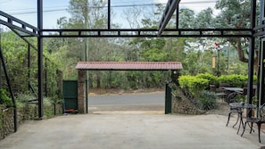 A covered entrance with a metal frame, a red roof, and a paved path leading inside.