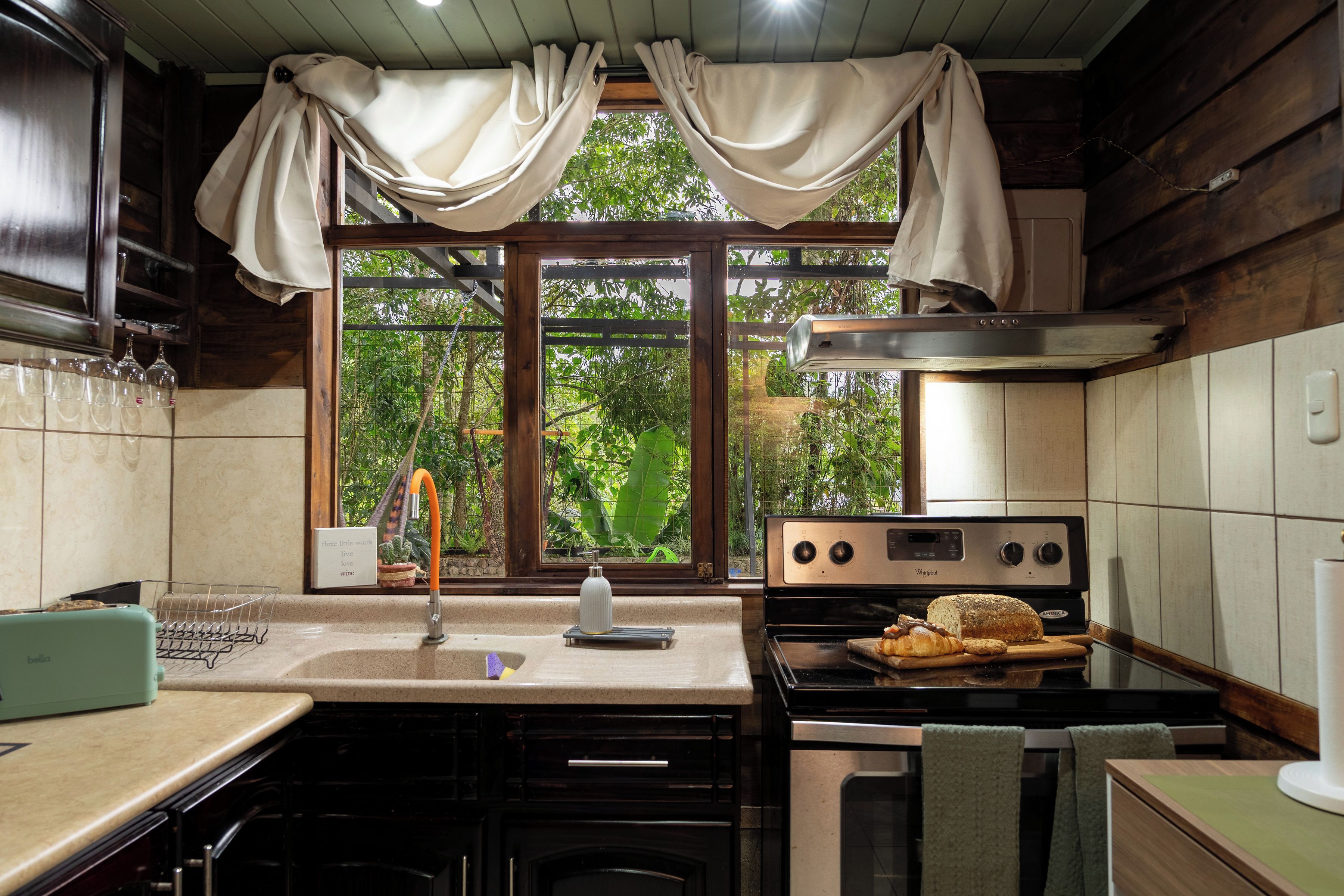 Une cuisine équipée d’une cuisinière, d’un four et d’une fenêtre avec des rideaux.