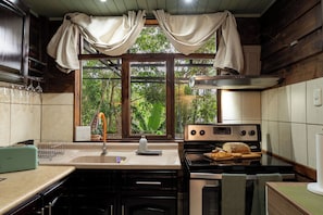 A kitchen with a stove, oven, and a window with curtains.